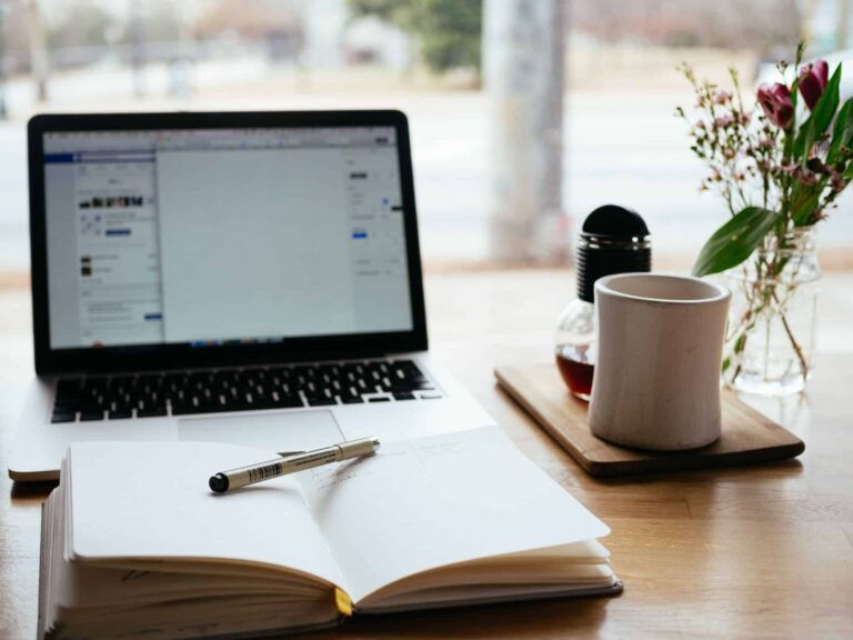 Laptop, notebook and coffee on wooden desk