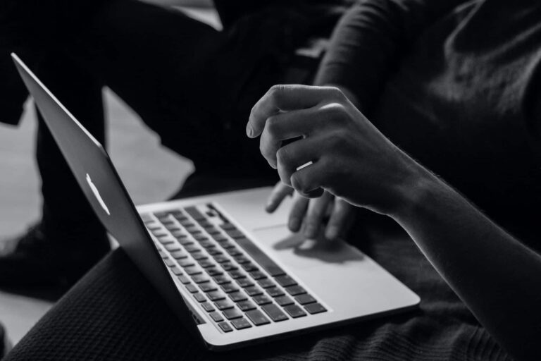 Person typing on laptop in black and white