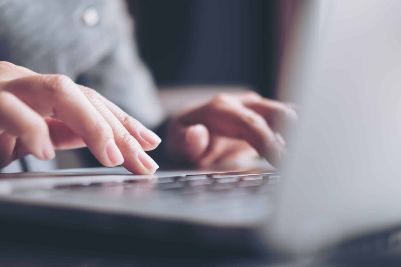 Close-up of hands typing on laptop keyboard