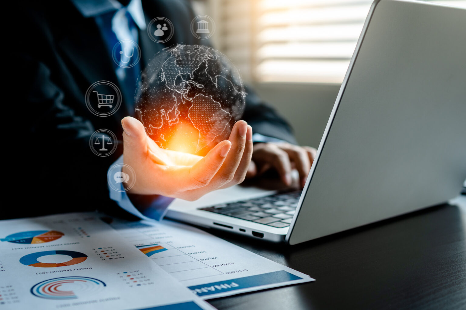 Businessperson holding glowing digital globe by laptop