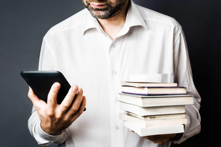 Man holding smartphone and stack of books