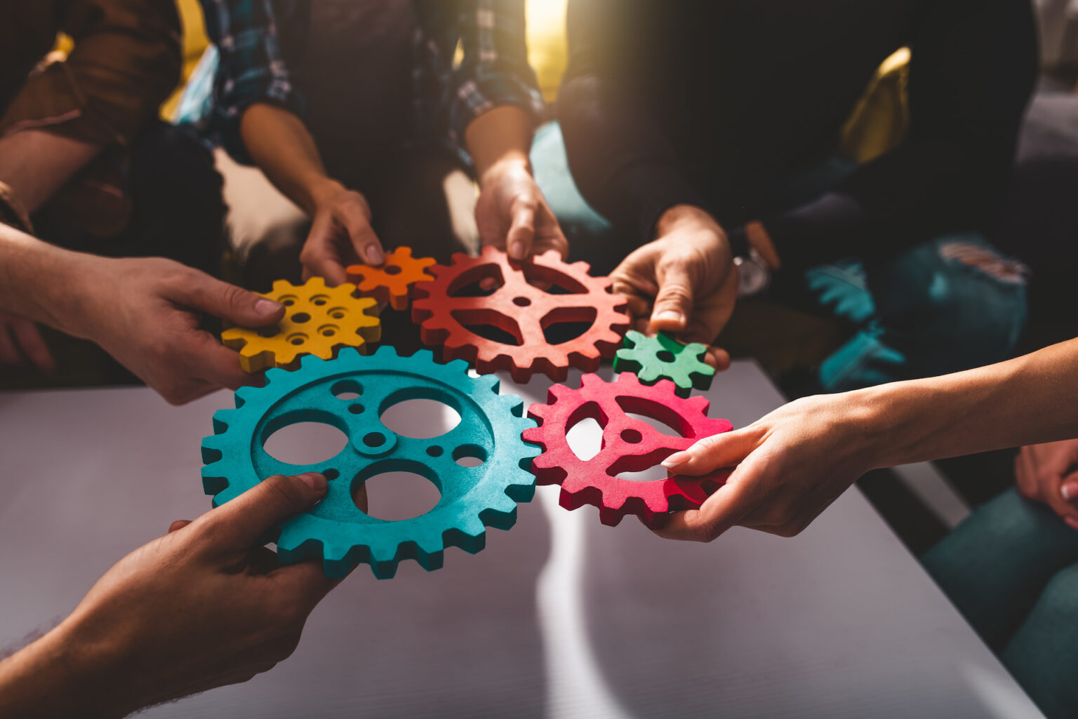 Hands holding colourful interlocking gears together