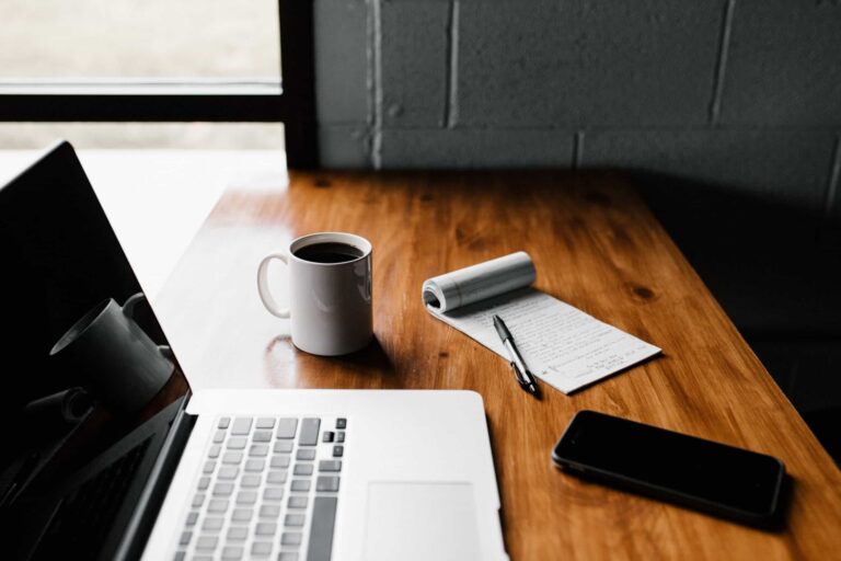 Laptop, coffee and notepad on wooden desk
