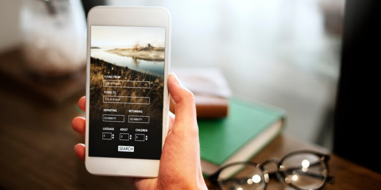 Hand holding smartphone with flight booking app