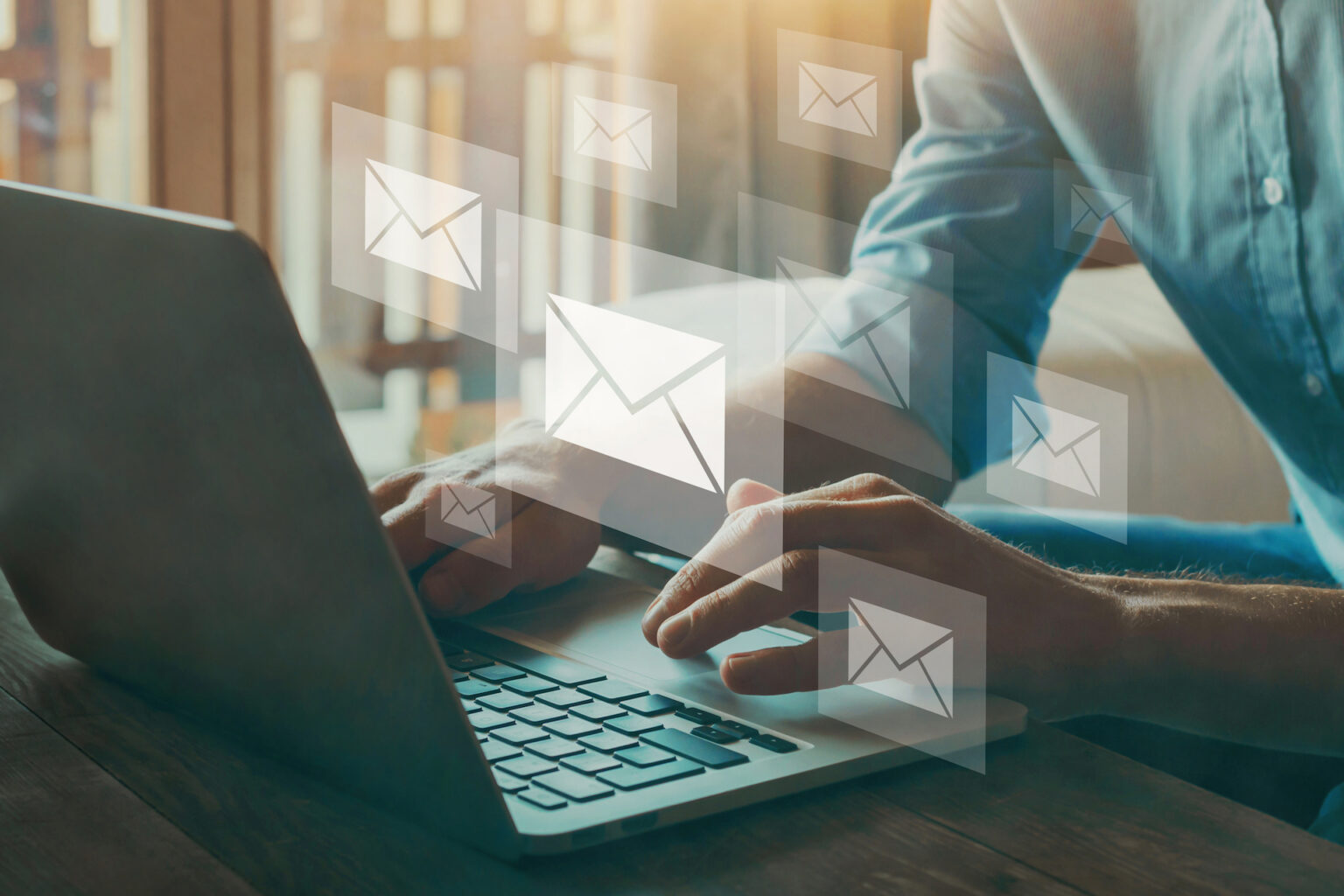 Person typing on laptop with email icons overlay