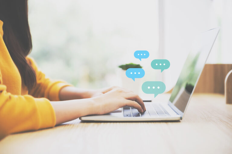 Person typing on laptop with chat icons