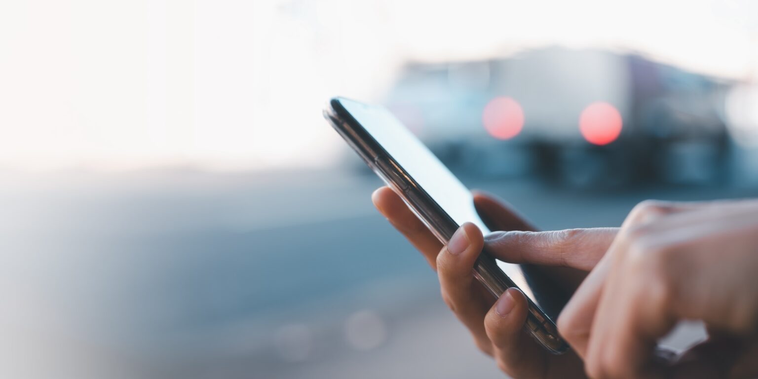 Hand holding smartphone at dusk outdoors