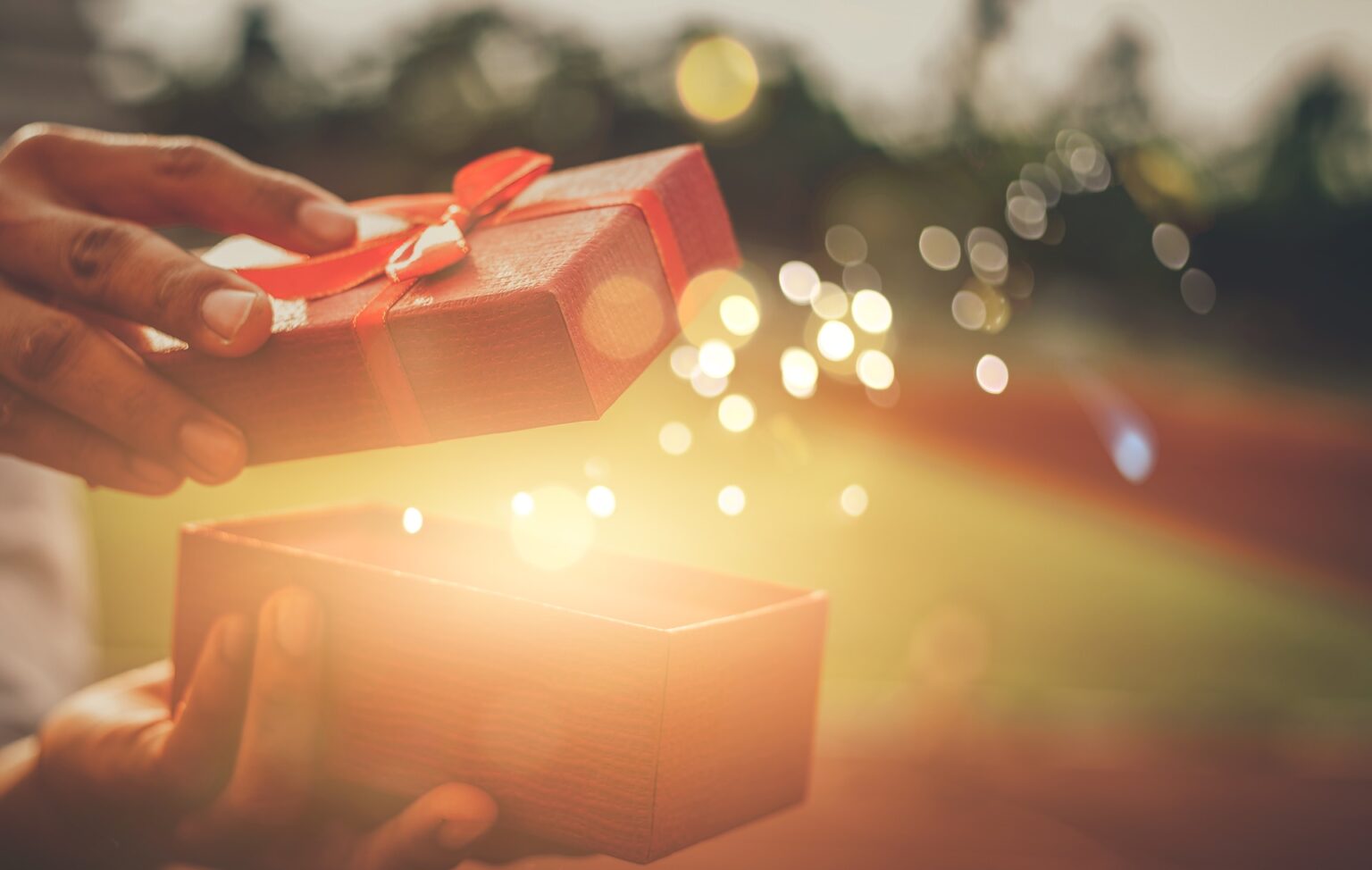Hands opening glowing red gift box