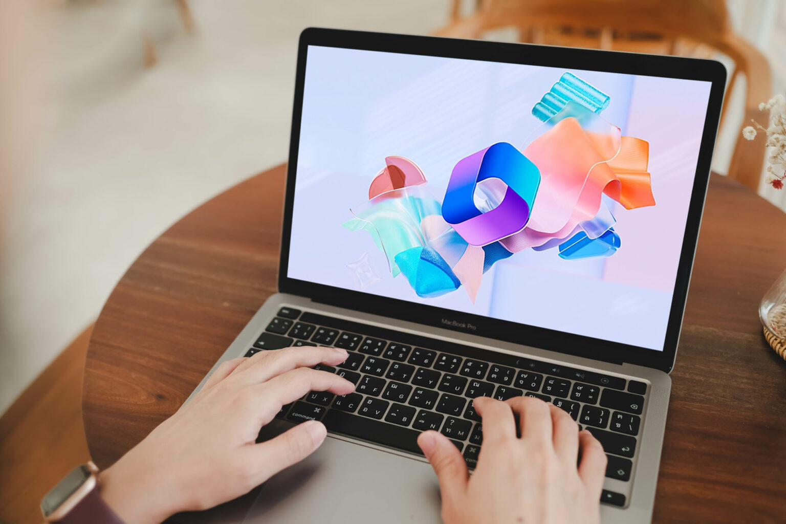 Hands typing on laptop with colourful abstract logo