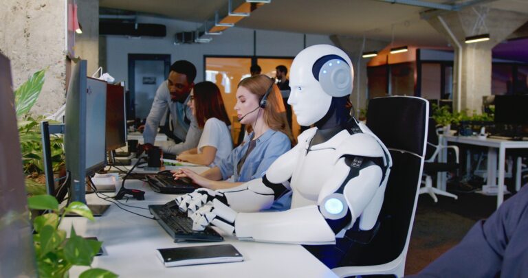 Humanoid robot working at computer in modern office