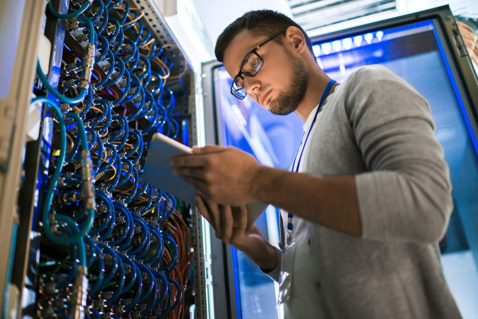 IT technician checking server cables with tablet