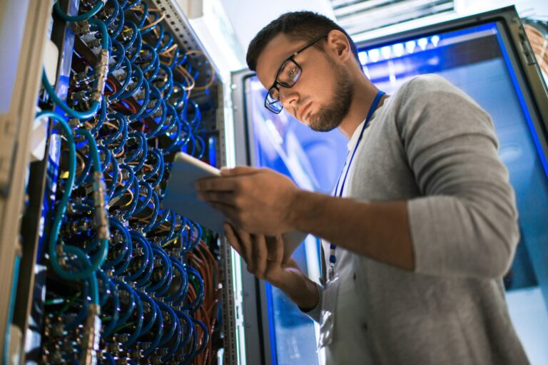 IT technician checking server cables with tablet
